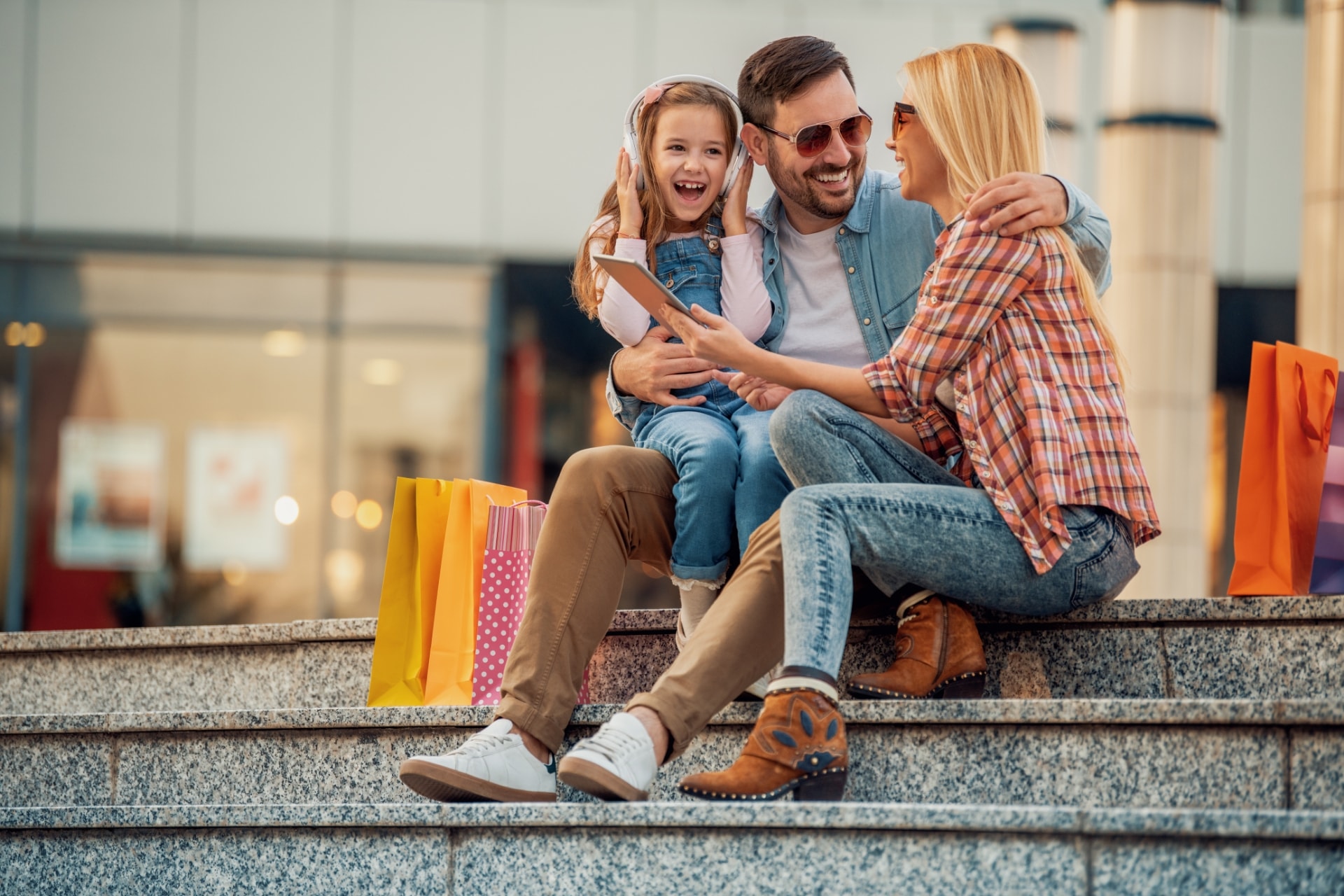 Family laughing sitting on steps with shopping bags